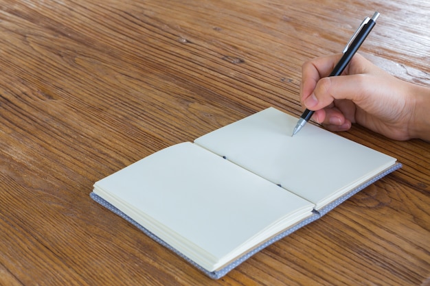 Dlon z dlugopisem nad notesem